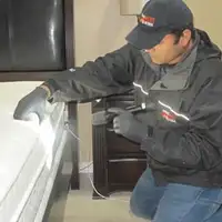 Bed bug inspection technician checking a mattress and bed frame for signs of infestation in Dayton, OH