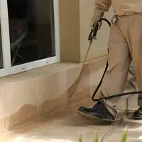 General pest control technician spraying exterior perimeter around a home in Dayton, OH