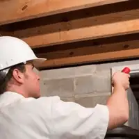 Termite inspection technician checking a basement wall and framing for termite activity in Dayton, OH