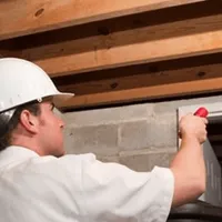 Termite inspection technician checking a basement wall and framing for termite activity in Dayton, OH